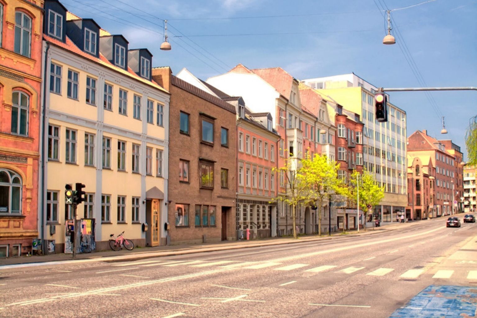 Bred gade med farvede ældre etageejendomme