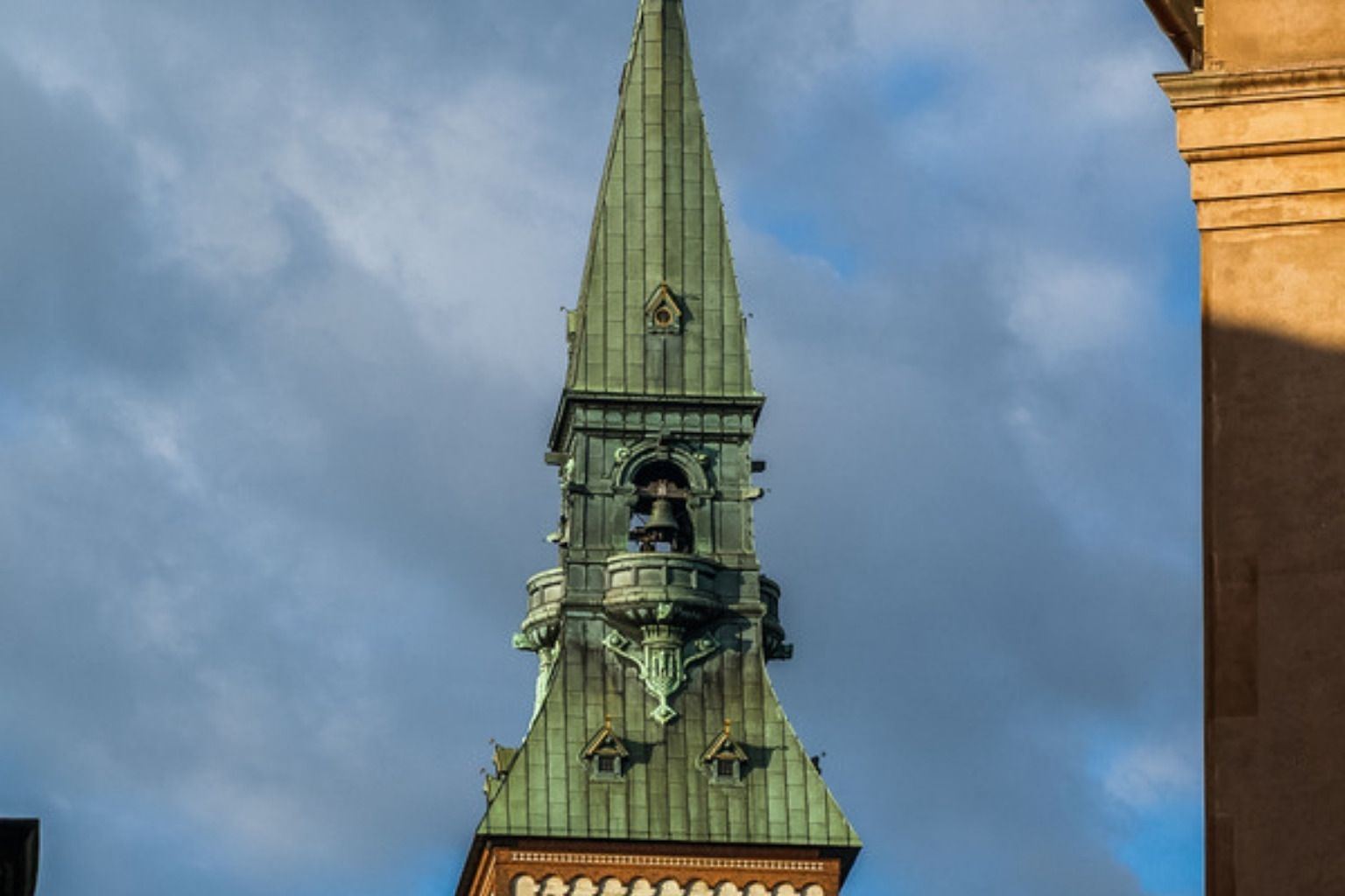 Grønt kobbertårn mod en skyet himmel
